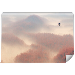 Samotny balon lecący nad lasem spowitym mgłą
