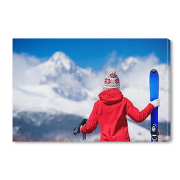 Młoda kobieta z nartami spoglądająca na góry