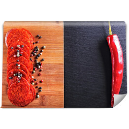 Salami z papryka chili i kolorowymi przyprawami na czarnym kamieniu i na drewnianej desce do krojenia