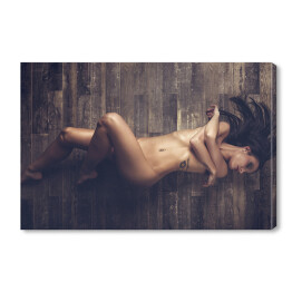 Młoda naga kobieta leżąca na drewnianej podłodze