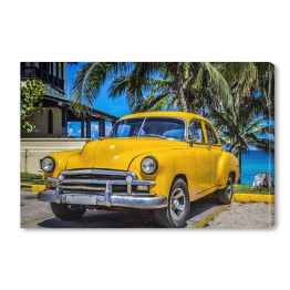 Żółty amerykański klasyczny samochód zaparkowany pod palmami na plaży w Varadero na Kubie 