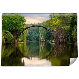 Odbijający się most w tafli rzeki w Parku Kromlau w Niemczech