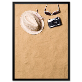 Okulary przeciwsłoneczne, wiklinowy kapelusz i aparat fotograficzny na piasku