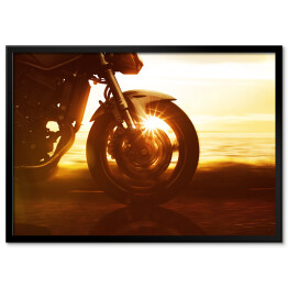 Koło motocyklu na tle złocistego zachodu słońca