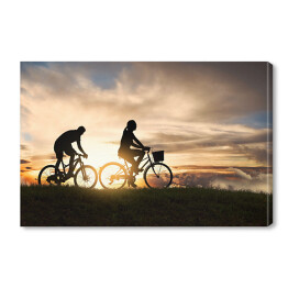 Młoda para jadąca rowerami o zachodzie słońca