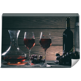 Wino w kieliszkach, karafki i butelki na drewnianym tle
