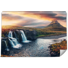 Niesamowity krajobraz górski z kolorowym żywym zachodem słońca na pochmurnym niebie nad słynnym wodospadem Kirkjufellsfoss i górą Kirkjufell. Islandia. popularna lokalizacja dla fotografów krajobrazowych.