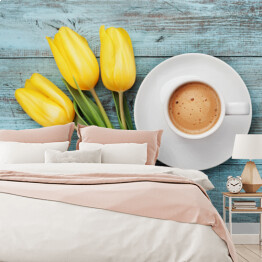 Kawowy kubek z żółtymi tulipanami i notatka na błękitnym stole