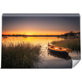 Fototapeta Mała łódka w trawie na jeziorze o zmierzchu