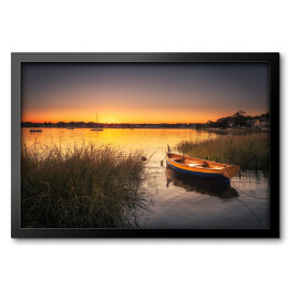 Obraz w ramie Mała łódka w trawie na jeziorze o zmierzchu