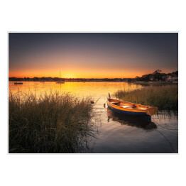 Plakat samoprzylepny Mała łódka w trawie na jeziorze o zmierzchu