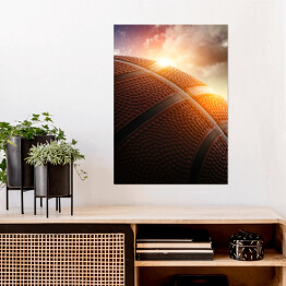 Plakat samoprzylepny Piłka do koszykówki oświetlona zachodzącym słońcem