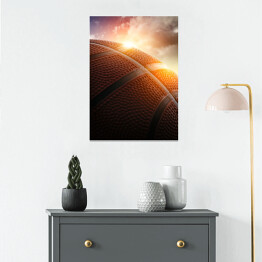 Plakat samoprzylepny Piłka do koszykówki oświetlona zachodzącym słońcem