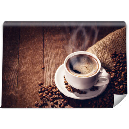 Fototapeta samoprzylepna Filiżanka i ziarna kawy na drewnianym tle