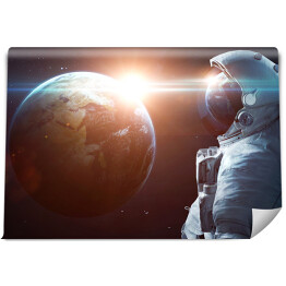 Fototapeta Astronauta w kosmosie podziwiający Słońce wyłaniające się zza planety