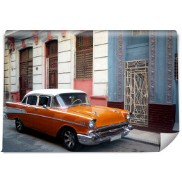 Pomarańczowy amerykański samochod na przedmieściach Hawany