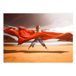 Kobieta unosząca się nad plażą w czerwonych tkaninach