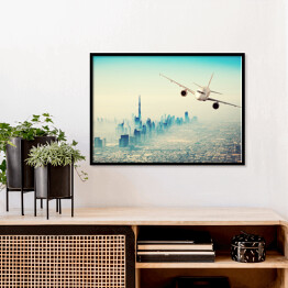 Plakat w ramie Samolot lecący nad miastem w sloneczny dzień