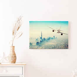 Obraz na płótnie Samolot lecący nad miastem w sloneczny dzień