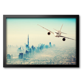 Obraz w ramie Samolot lecący nad miastem w sloneczny dzień