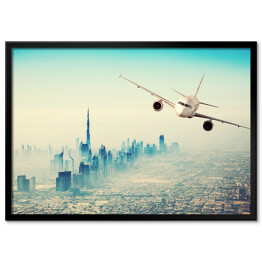 Plakat w ramie Samolot lecący nad miastem w sloneczny dzień