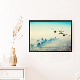 Obraz w ramie Samolot lecący nad miastem w sloneczny dzień