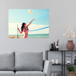 Plakat samoprzylepny Młoda kobieta z piłką grająca w siatkówkę na plaży