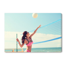 Młoda kobieta z piłką grająca w siatkówkę na plaży