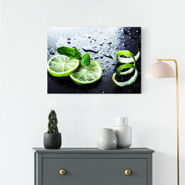 Obraz na płótnie Zielone limonki z miętą i wodą spadające na czarnym tle