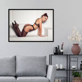 Plakat w ramie Kobieta w uwodzicielskiej czarnej bieliźnie siedząca na kanapie w pończochach