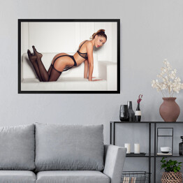 Obraz w ramie Kobieta w uwodzicielskiej czarnej bieliźnie siedząca na kanapie w pończochach