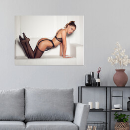 Plakat Kobieta w uwodzicielskiej czarnej bieliźnie siedząca na kanapie w pończochach