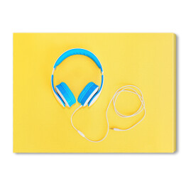 Obraz na płótnie Niebieskie słuchawki leżące na żółtym tle