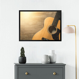 Obraz w ramie Gitara akustyczna oświetlona światłem słonecznym na drewnianym tle 
