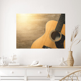 Plakat Gitara akustyczna oświetlona światłem słonecznym na drewnianym tle 