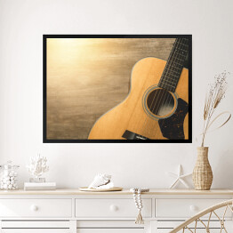 Obraz w ramie Gitara akustyczna oświetlona światłem słonecznym na drewnianym tle 
