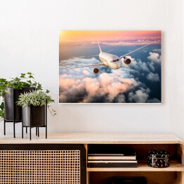 Obraz na płótnie Samolot nad chmurami na kolorowym niebie