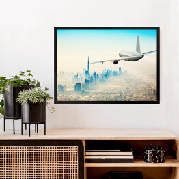 Obraz w ramie Samolot latający nad nowoczesnym miastem w jasnych barwach