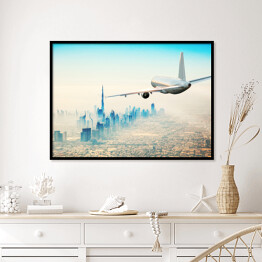Plakat w ramie Samolot latający nad nowoczesnym miastem w jasnych barwach
