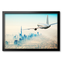 Obraz w ramie Samolot latający nad nowoczesnym miastem w jasnych barwach