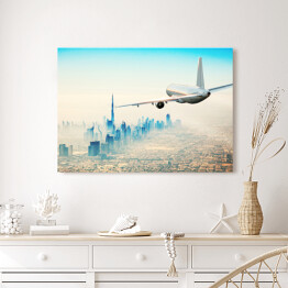 Obraz na płótnie Samolot latający nad nowoczesnym miastem w jasnych barwach