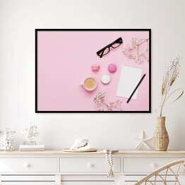 Plakat w ramie Kawa, ciasto makaron, czysty notatnik, okulary i kwiat na różowym stole