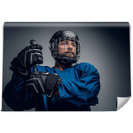 Fototapeta Brodaty hokeista w kasku trzymający kij do gry