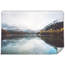 Fototapeta samoprzylepna Mglisty krajobraz jeziora na tle gór
