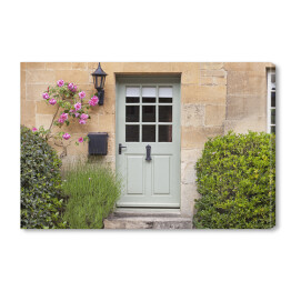 Obraz na płótnie Jasne drewniane drzwi w starej tradycyjnej angielskiej chałupie w otoczeniu wspinaczki róż i lawendy