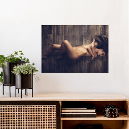 Plakat samoprzylepny Młoda naga kobieta leżąca na drewnianej podłodze