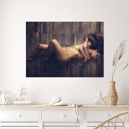 Plakat samoprzylepny Młoda naga kobieta leżąca na drewnianej podłodze