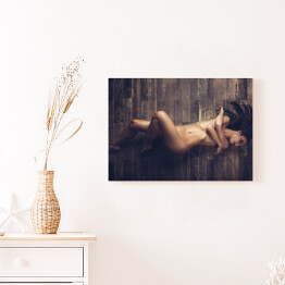 Obraz na płótnie Młoda naga kobieta leżąca na drewnianej podłodze