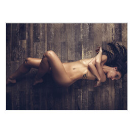 Plakat Młoda naga kobieta leżąca na drewnianej podłodze