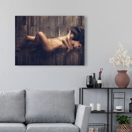 Obraz na płótnie Młoda naga kobieta leżąca na drewnianej podłodze